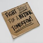 Cardboard sign with 'Fight today for a better tomorrow!' message on a white background.